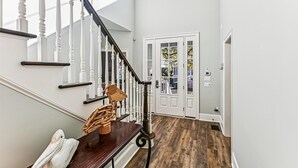 A staircase with white balusters and a dark handrail leading to a door with glass panels. - 13 Moonshell, Close to Beach, Pool, Big Backyard, Free Golf, Dogs Welcome (Hilton Head)
