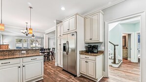A spacious kitchen with white cabinetry, a stainless steel refrigerator, and a granite countertop. - 13 Moonshell, Close to Beach, Pool, Big Backyard, Free Golf, Dogs Welcome (Hilton Head)