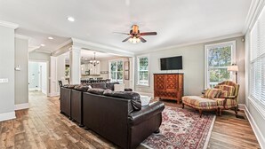A spacious living room with a dark leather sofa, a patterned rug, and a wooden cabinet. - 13 Moonshell, Close to Beach, Pool, Big Backyard, Free Golf, Dogs Welcome (Hilton Head)