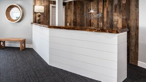 A reception desk with a wooden accent, a round mirror, and a wall-mounted lamp.