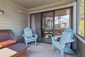 En overdækket veranda med fletmøbler og Adirondack-stole.