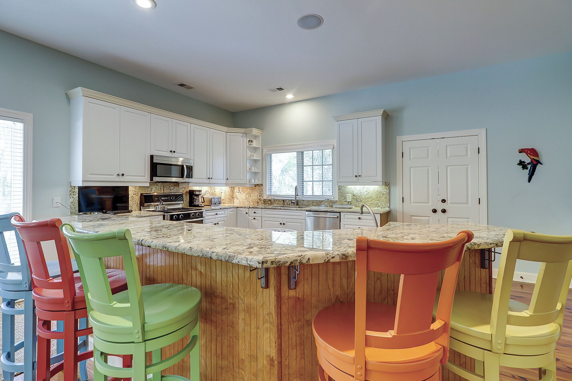 A kitchen with white cabinets, a granite countertop, and a central island with bar stools.