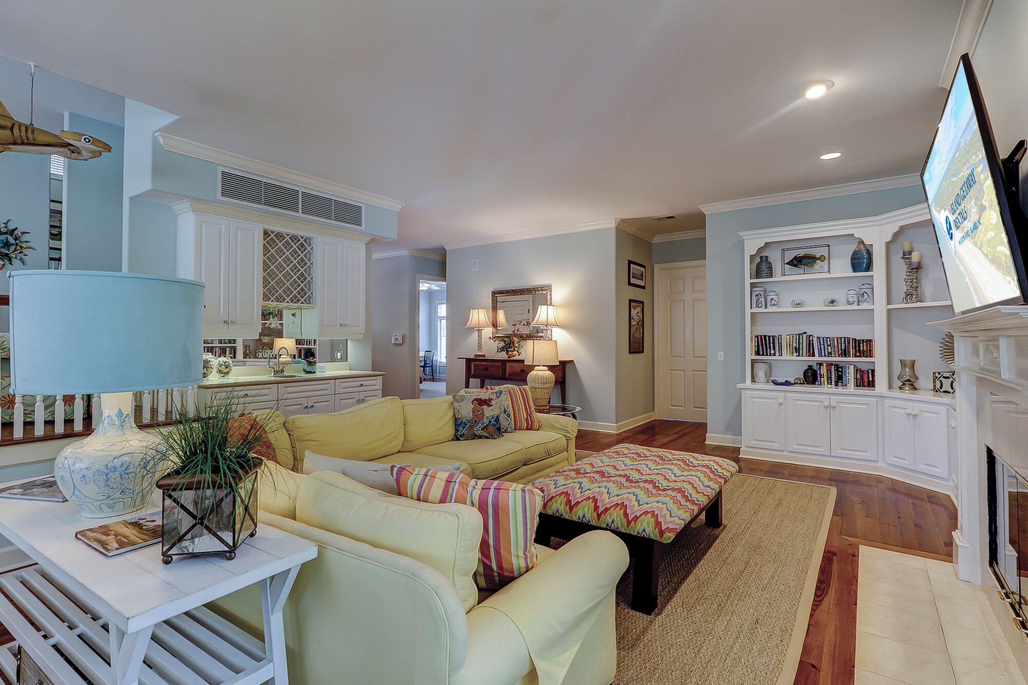 A living room with a yellow sofa, a coffee table, and a bookshelf.