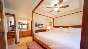 Ein Schlafzimmer mit einem Himmelbett, einem Deckenventilator, einem Holz-Kopfteil und einer Sitzbank.