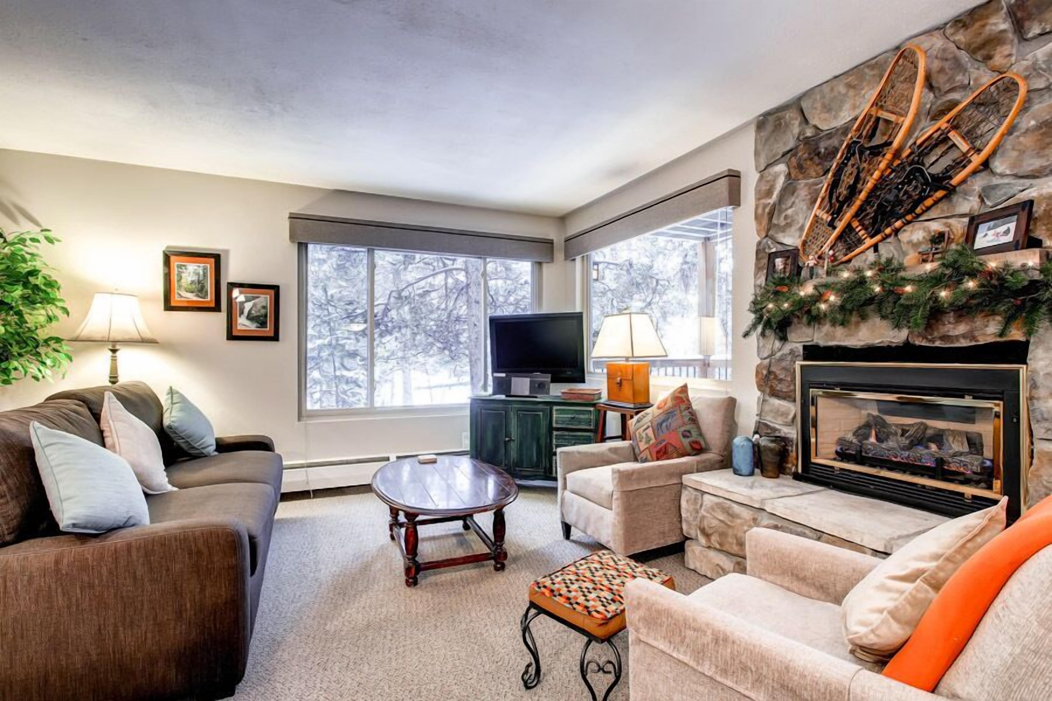 A living room with a stone fireplace, a television, and a large window.