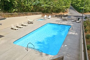 A rectangular outdoor swimming pool with a metal ladder, surrounded by lounge chairs and tables. - Cabin close to downtown w/Theater|Gameroom|Hot Tub (PIGEON FORGE)