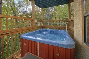 A hot tub on a wooden deck with a view of trees.