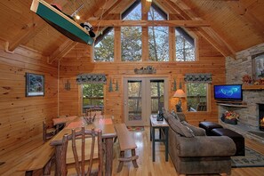 A cozy cabin interior with a wooden dining table, benches, a sofa, and a fireplace. - Cabin close to downtown w/Theater|Gameroom|Hot Tub (PIGEON FORGE)