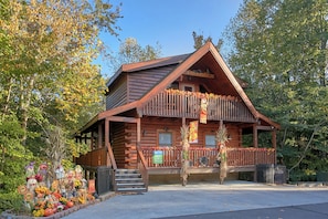 A log cabin with a porch, surrounded by autumn foliage.