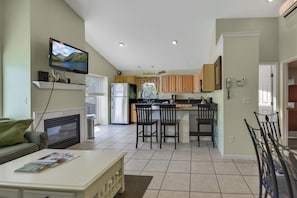 A modern kitchen with a dining area, a TV mounted on the wall, and a fireplace.