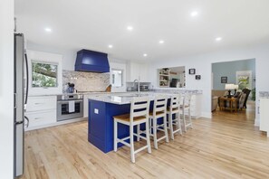A modern kitchen with a large island, white cabinetry, and a blue accent wall.