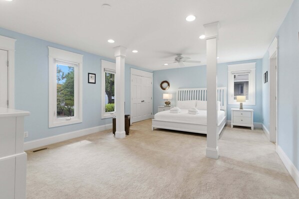A bedroom with a bed, nightstands, a ceiling fan, and a window.