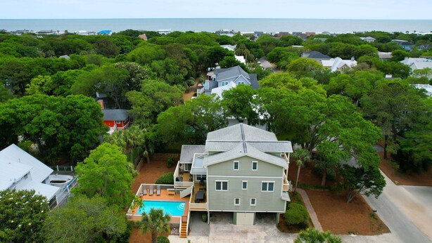 Ein zweigeschossiges Haus mit Swimmingpool, umgeben von üppiger Vegetation und Blick auf das Meer.
