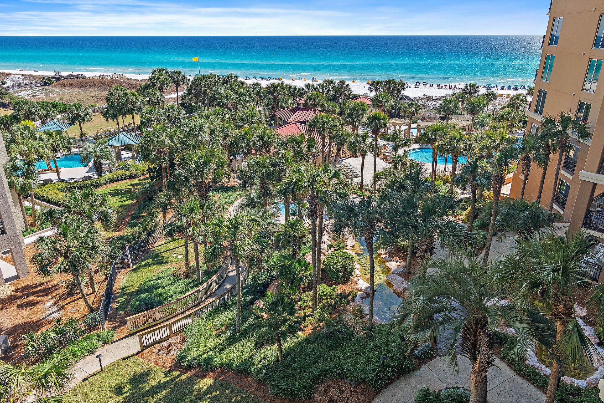 Un resort con piscina, palmeras y vista al mar.