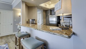 Una cocina moderna con encimeras de granito, electrodomésticos de acero inoxidable y una zona de bar con taburetes.