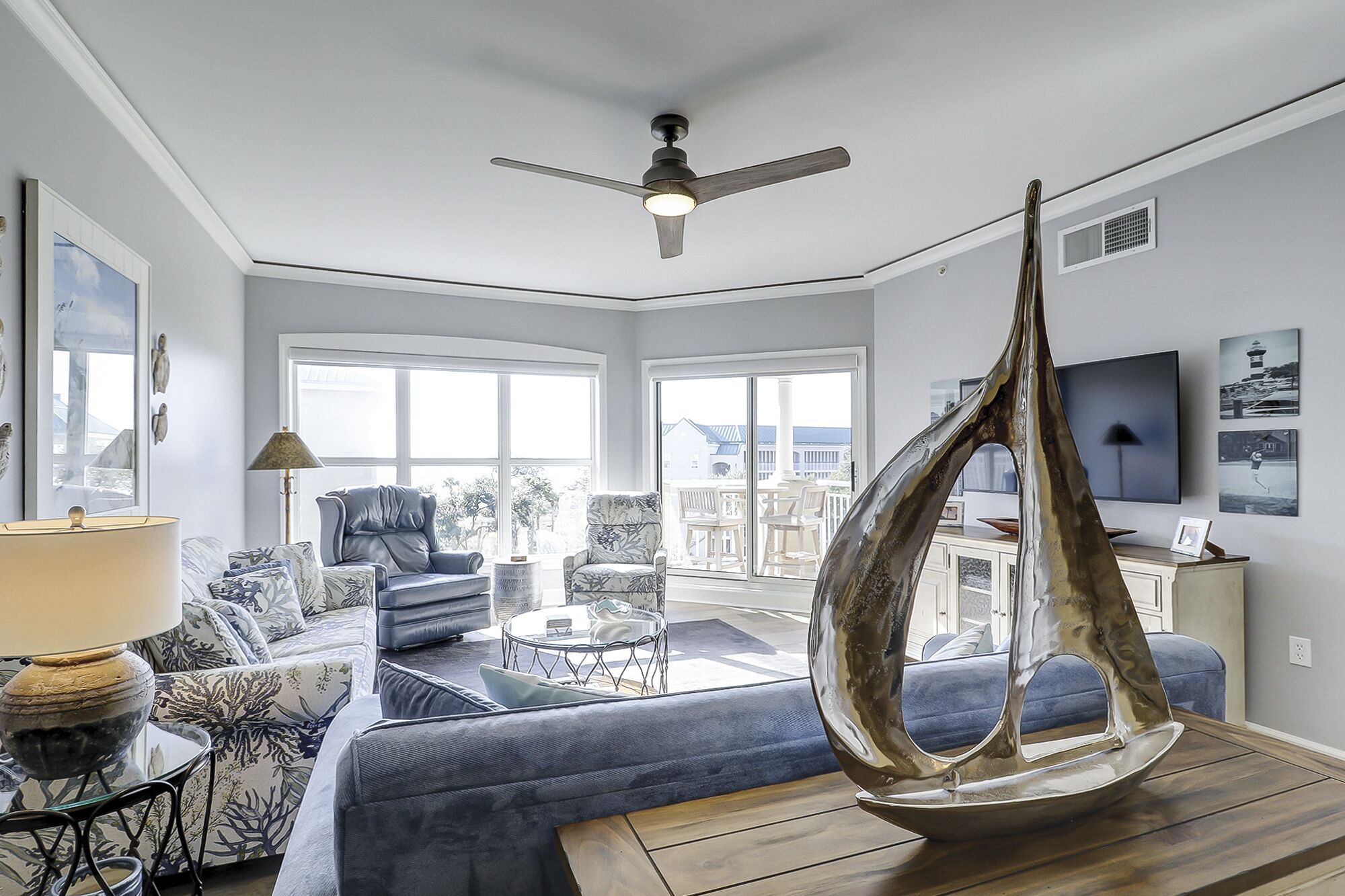 A modern living room with a blue sofa, a coffee table, and a unique metallic sculpture.