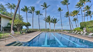 Piscina com espreguiçadeiras e palmeiras.