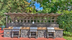 Uma churrasqueira com parede de pedra e pérgola de madeira.