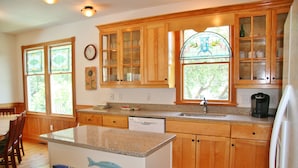 A kitchen with wooden cabinets, a granite countertop, a dishwasher, and a refrigerator. - Waves of Grace: Private Pool, Hot Tub, Screened Porch (Corolla)