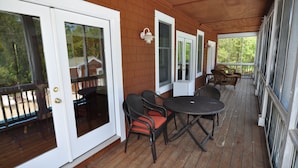 A wooden deck with a table and chairs, a door, and a window. - Waves of Grace: Private Pool, Hot Tub, Screened Porch (Corolla)