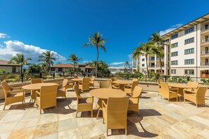 Un patio al aire libre con mobiliario de mimbre y vistas a un edificio de varios pisos.