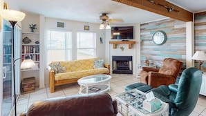 Una sala de estar con sofá, sillón, mesa de centro, chimenea y televisor.