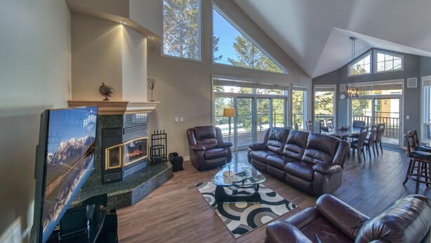 A spacious living room with a fireplace, leather furniture, and large windows offering views of the outdoors.