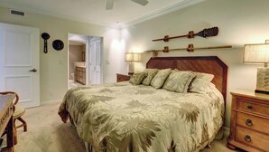 A bedroom with a bed, bedside tables, a ceiling fan, and a door.