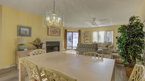 Ein geräumiges Wohnzimmer mit Kamin, eine Essecke mit großem Tisch und Stühlen sowie ein Deckenventilator.
