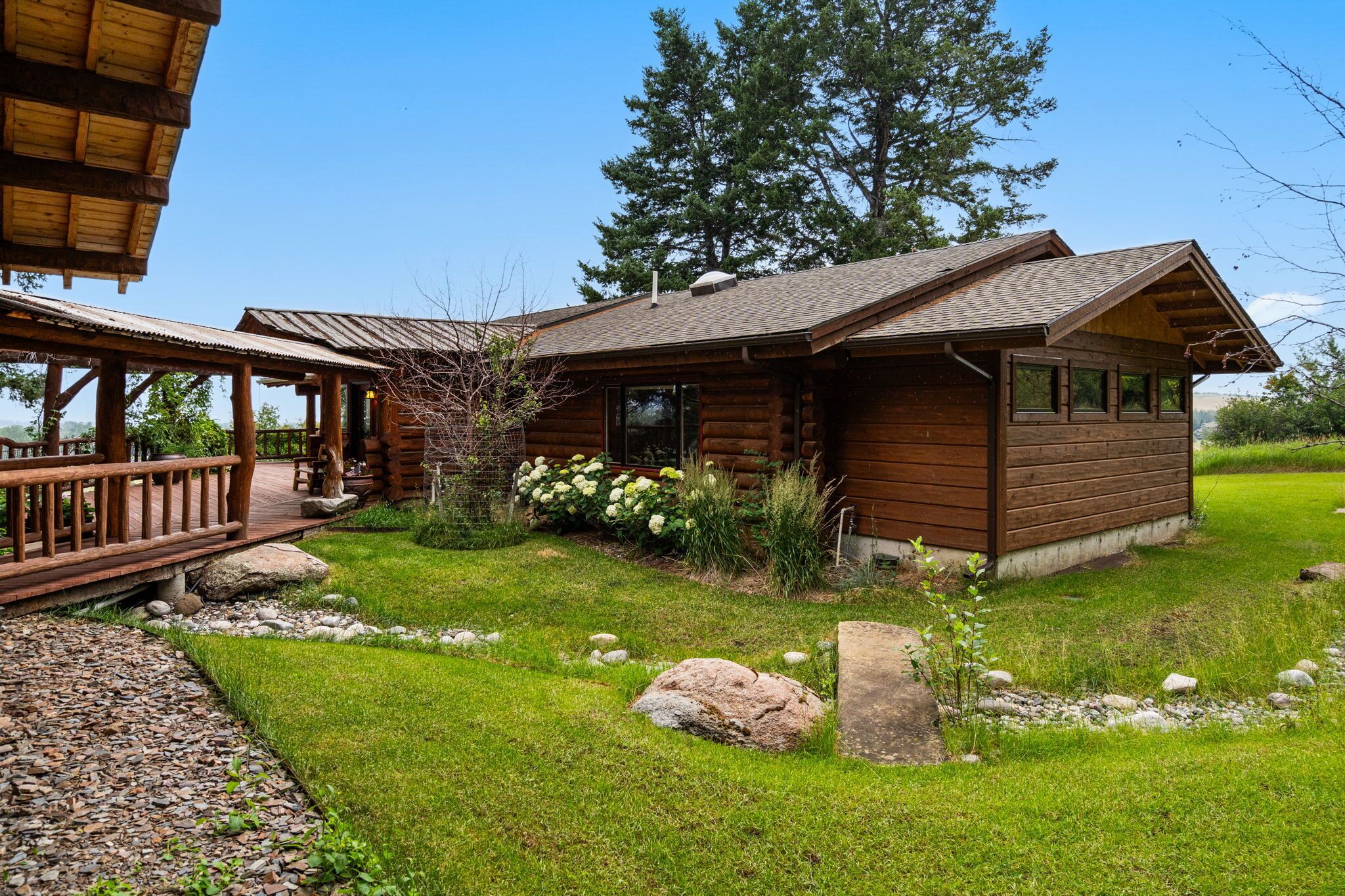 A rustic log cabin with a wooden deck and a covered porch.