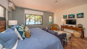 A bedroom with a large bed, a television, and artwork on the wall. - Beautiful Hacienda style villa located on white sandy beach, pool, AC, WiFi! (South Akumal)