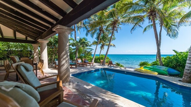 A pool area with lounge chairs and a view of the ocean. - Beautiful Hacienda style villa located on white sandy beach, pool, AC, WiFi! (South Akumal)