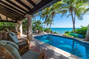 A pool area with lounge chairs and a view of the ocean. - Beautiful Hacienda style villa located on white sandy beach, pool, AC, WiFi! (South Akumal)