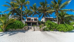 A beachfront property with a two-story building, surrounded by palm trees and a sandy beach. - Beautiful Hacienda style villa located on white sandy beach, pool, AC, WiFi! (South Akumal)