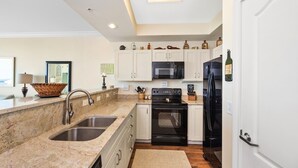 Una cocina moderna con un lavamanos doble, electrodomésticos de acero inoxidable, armarios blancos y un ventanal sobre la encimera.