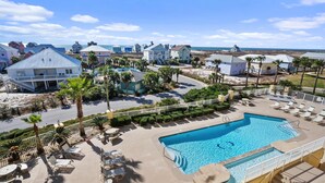 Un resort con piscina, sillas de descanso y vista al océano.