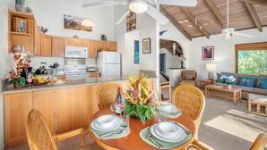 A spacious kitchen with wooden cabinets, a white refrigerator, and a dining area with a round table set for four.