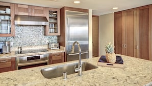 A kitchen with granite countertops, stainless steel appliances, wooden cabinets, and a tiled backsplash. - Maui Resort Rentals: Hyatt Residence Club – 2BR Oceanfront Middle Floor VIlla (Lahaina)
