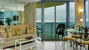 A living room with a sofa, coffee table, and a balcony with a view of the ocean.