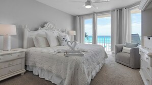 A bedroom with a bed, nightstands, a chair, and a ceiling fan.
