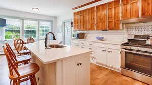 Una cocina moderna con armarios de madera, una isla grande con fregadero y una estufa de acero inoxidable.