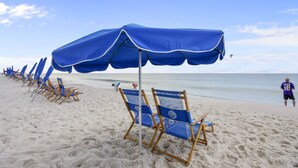 A beach with rows of blue beach chairs and umbrellas. - The Oasis at Orange Beach 2114 | Lazy River, Water Slide | My Beach Getaways (Orange Beach)