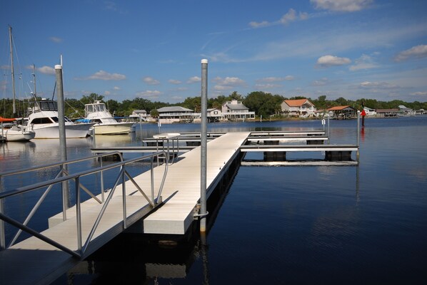 A marina with docked boats, a pier, and houses in the background.