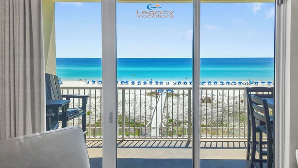 A balcony with a view of the beach and ocean.