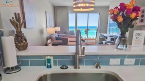 A modern kitchen with a stainless steel sink, a towel rack, and a vase with flowers.