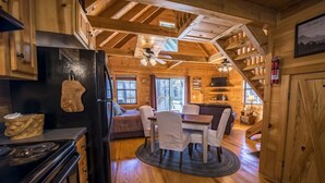 A log cabin interior with a kitchen, dining area, and living space.