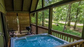 A hot tub on a wooden deck with a view of a forested area.