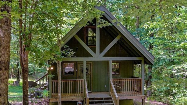 A cabin with a porch, a staircase, and a deck.