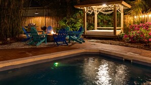 A pool area with a gazebo, outdoor seating, and a fire pit. - Guiding Light Cottage | Heated Saltwater Pool (Tybee Island)