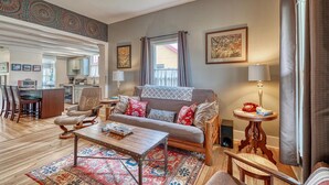 A living room with a sofa, coffee table, and chairs, a dining area with a table and chairs, and a kitchen in the background. - Nita's Place- Live like a local! Close to town! (Salida)